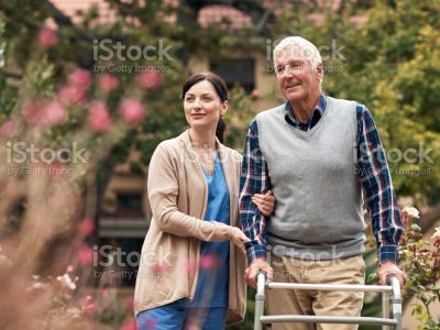 Shot of a senior man with his walker out for a stroll in the garden with his caregiver